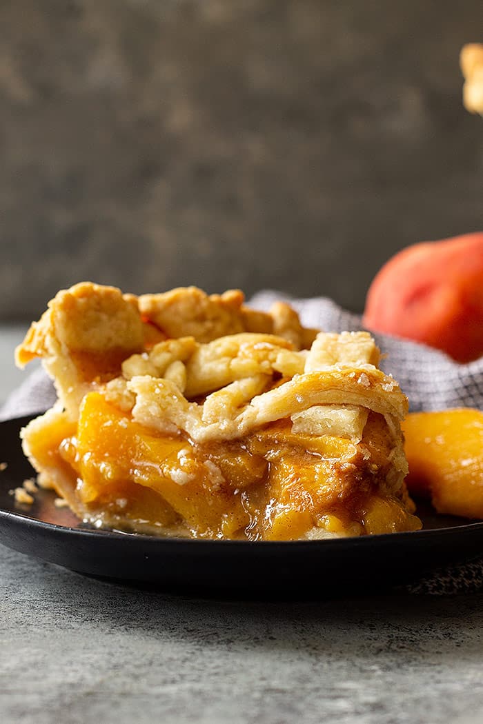 A slice of peach pie with an all butter crust.