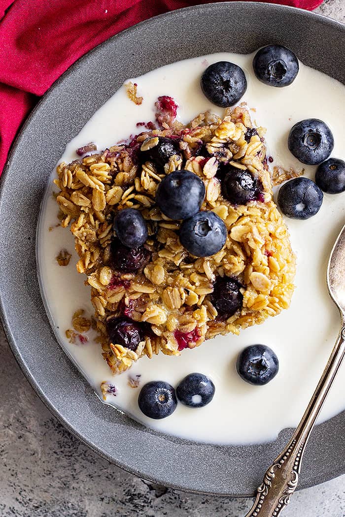 Baked oatmeal in a bowl topped with fresh blueberries and a splash of milk.