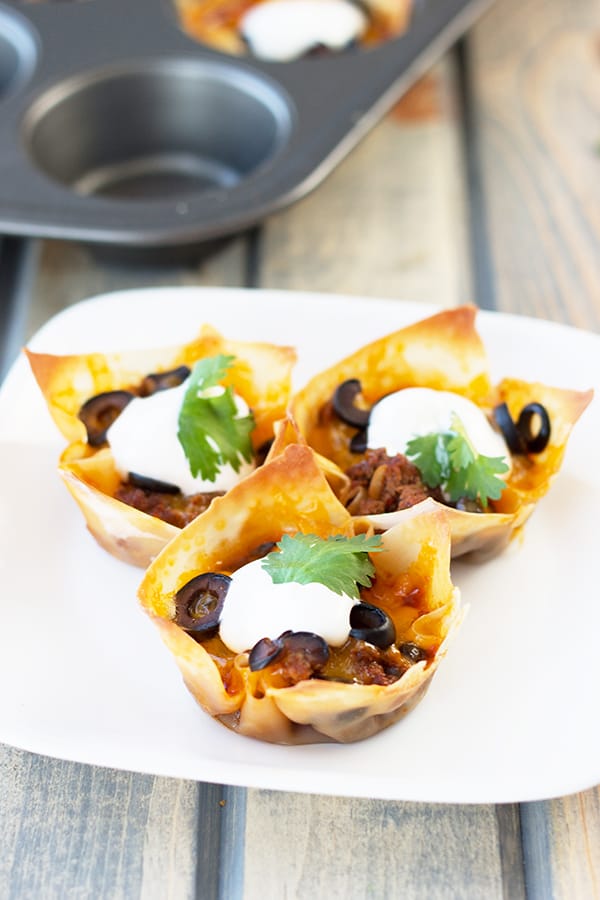 Beef Enchilada Cups- an easy and oh so tasty game day appetizer. Filled with seasoned beef, black beans, cheddar, black olives and topped with creamy sour cream. | Countryside Cravings