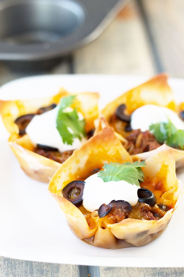 Beef Enchilada Cups- an easy and oh so tasty game day appetizer. Filled with seasoned beef, black beans, cheddar, black olives and topped with creamy sour cream. | Countryside Cravings