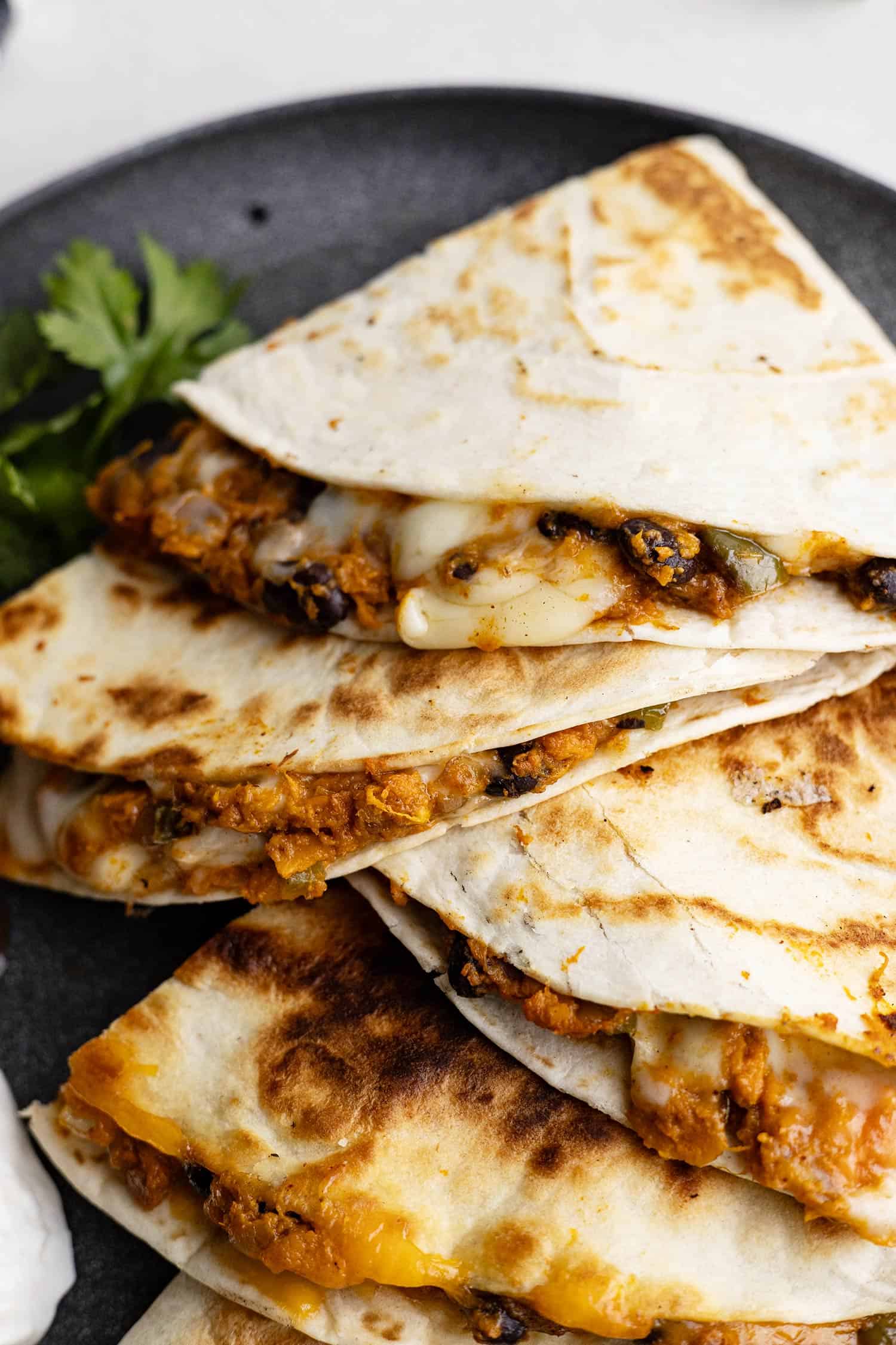 Quesadillas staggered on a plate. Can see the melty cheese. 