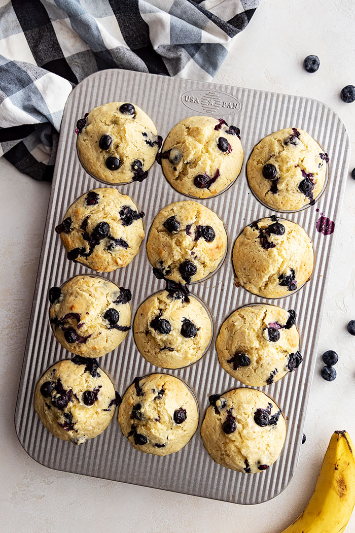 Overhead view of blueberry banana muffins fresh from the oven. Blueberries scattered off to the side.