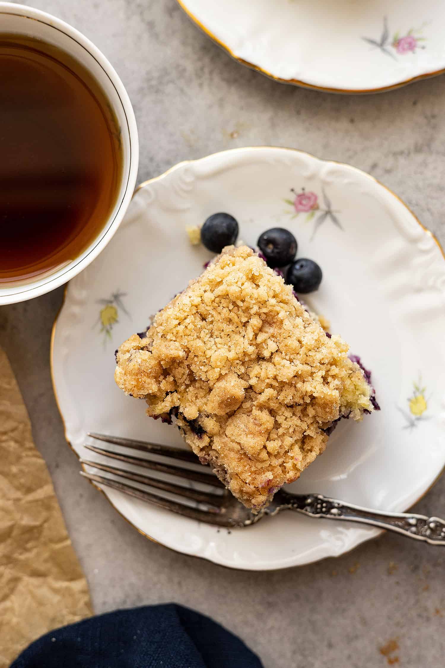 Overhead view of cake on a plate with fork and coffee off to the side. 