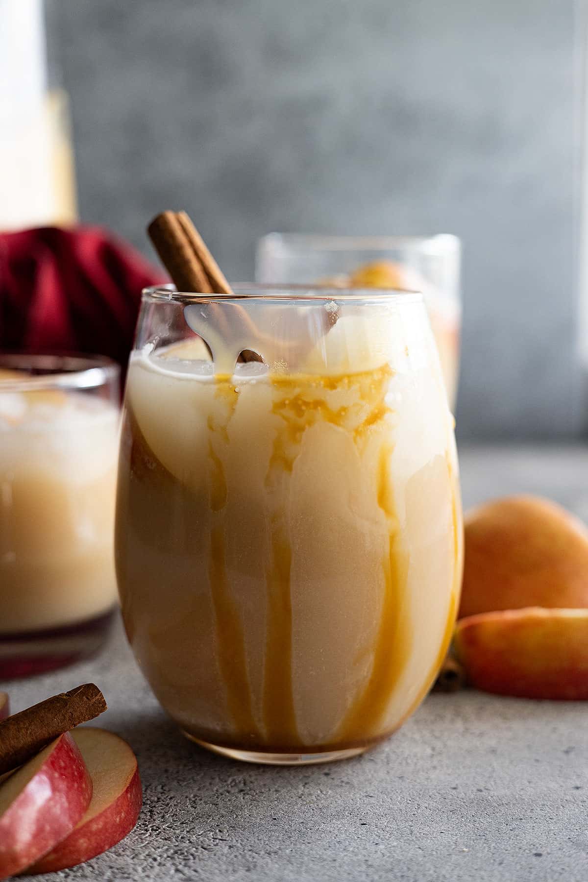 Sangria in a glass with caramel drizzle down the side. Apple slices and cinnamon stick to garnish. 