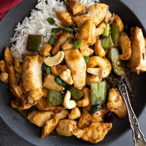 Overhead view of stirfry on a plate with white rice. Red napkin off to the side.