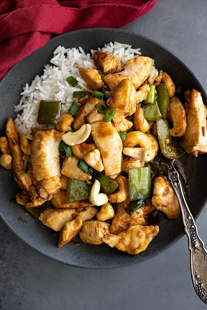 Overhead view of stirfry on a plate with white rice. Red napkin off to the side. 