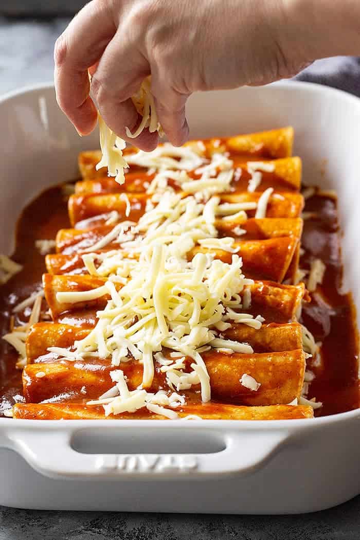 adding cheese to top of enchiladas