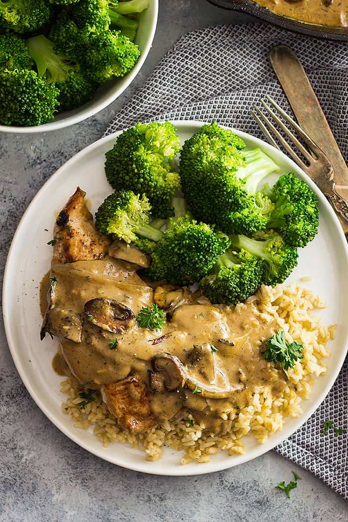 White plate with broccoli, rice, chicken, and a mushroom cream sauce drizzled on top