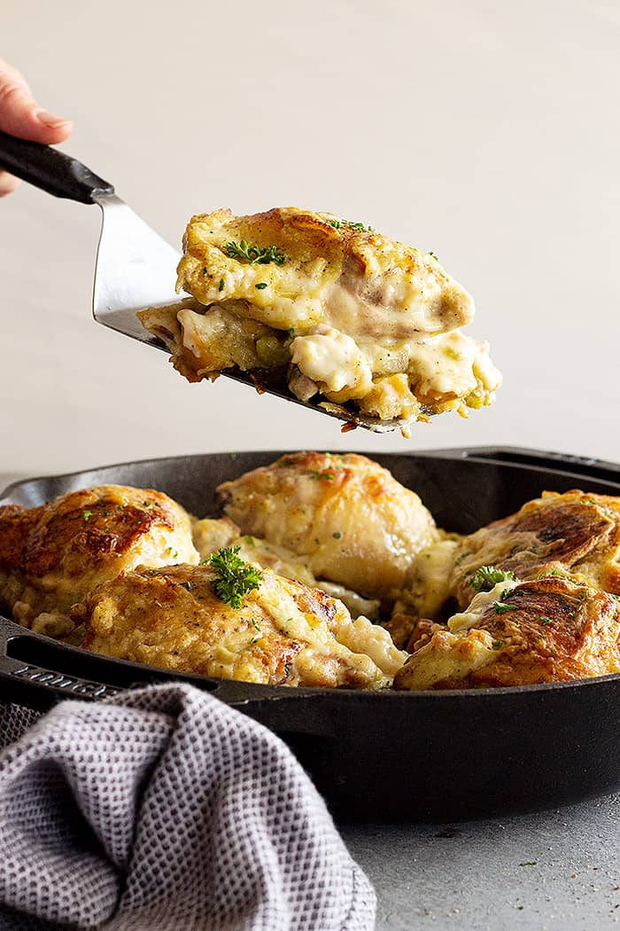 Lifting a portion of the casserole out of the pan ready to serve onto a plate. 