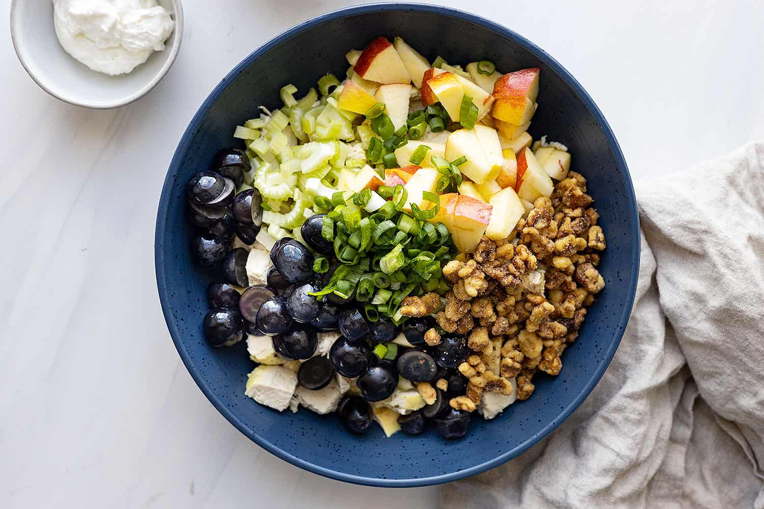 Overhead of all the ingredients in separate piles in a large dark blue bowl ready to be stirred. 