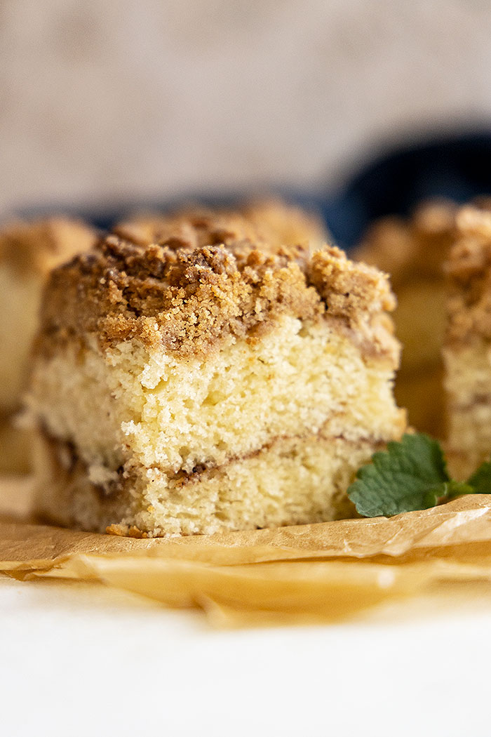 A piece of coffee cake showing the cinnamon middle and crumb topping. 