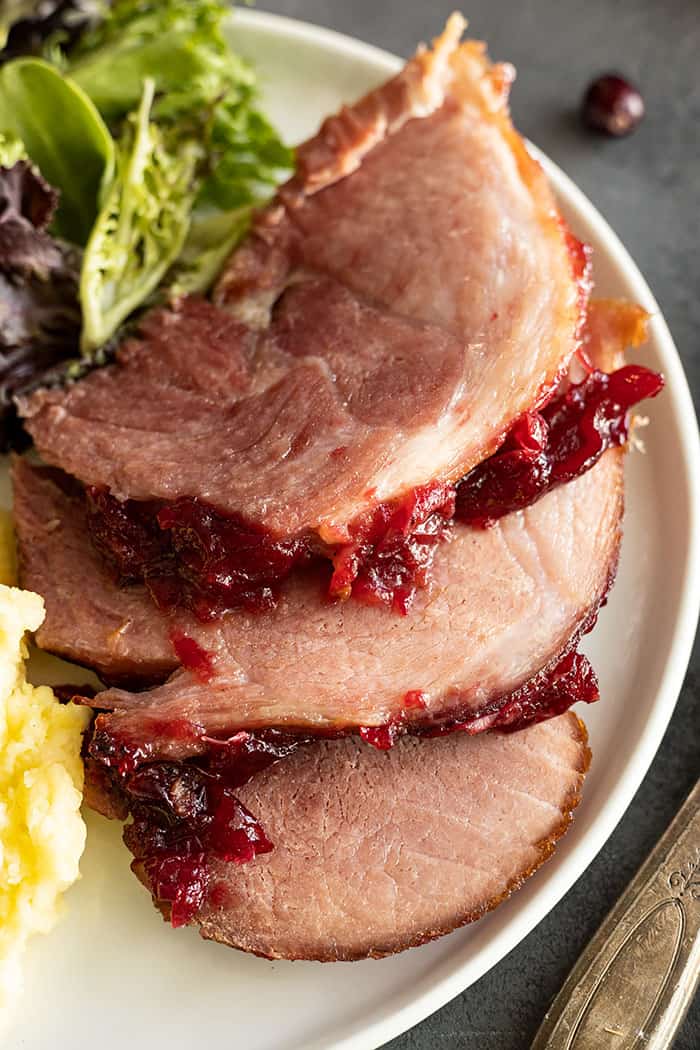 Overhead view of ham slices on a white plate. 