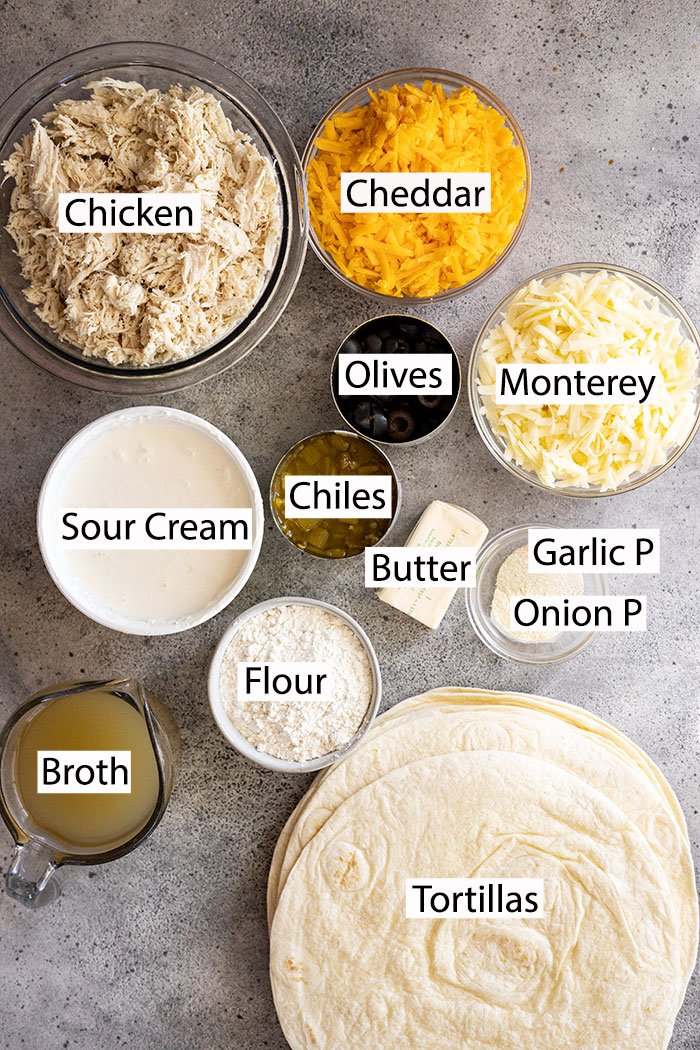 Ingredients to make white chicken enchiladas: chicken, cheddar, mozzarella, olives, chiles, sour cream, broth, flour, butter, garlic powder, onion powder, tortillas.