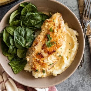 Overhead view of chicken on a plate with mashed potatoes and a side salad.