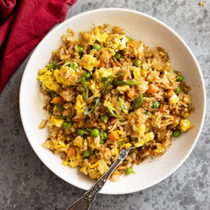 Overhead view of fried rice in a bowl garnished with green onion.