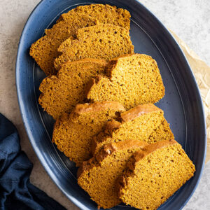 Overhead view of several slices of pumpkin bread staggered on a blue plate.