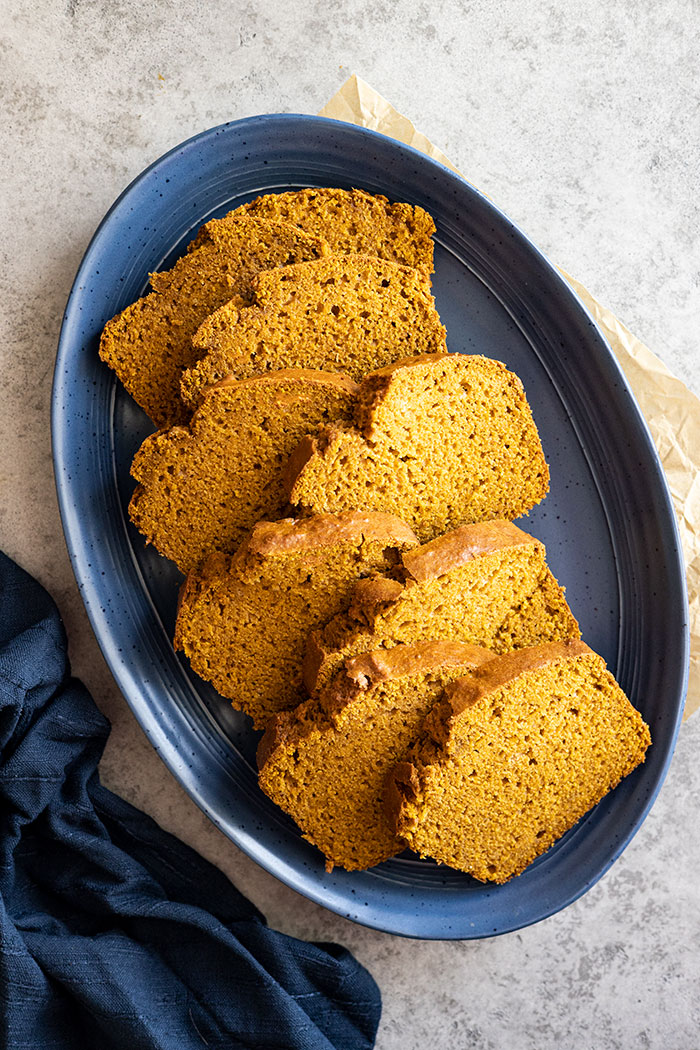 Overhead view of several slices of pumpkin bread staggered on a blue plate. 