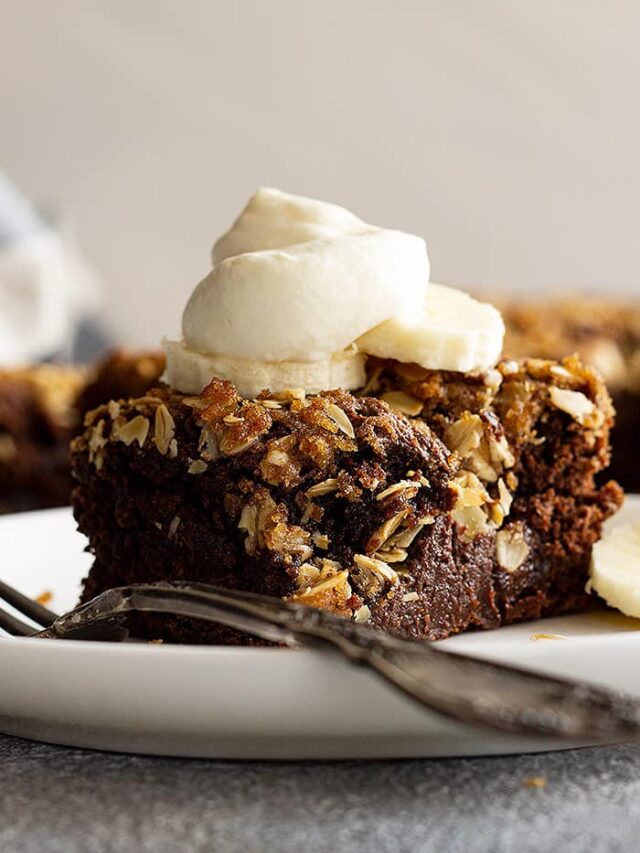 A slice of cake topped with whipped cream and banana slices.