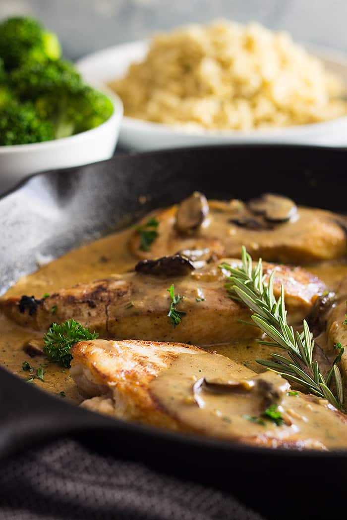 chicken in mushroom cream sauce with fresh rosemary in black skillet