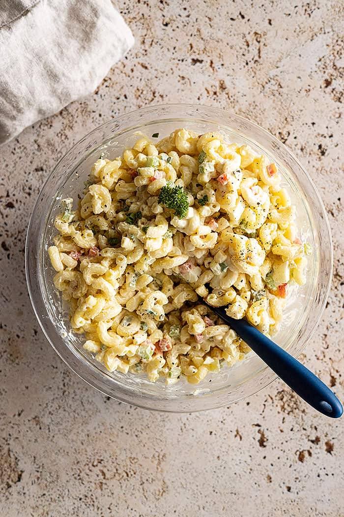 overhead: grandma's old fashioned macaroni salad recipe in a bowl garnished with black pepper and parsley