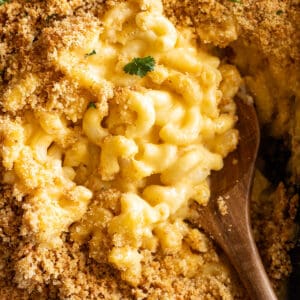 Overhead view of homemade mac and cheese in a casserole dish fresh from the oven. Wooden spoon dipping into the dish.