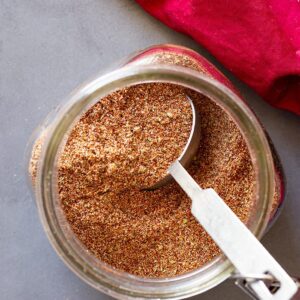 Top down of taco seasoning in a jar with a measuring spoon in it.