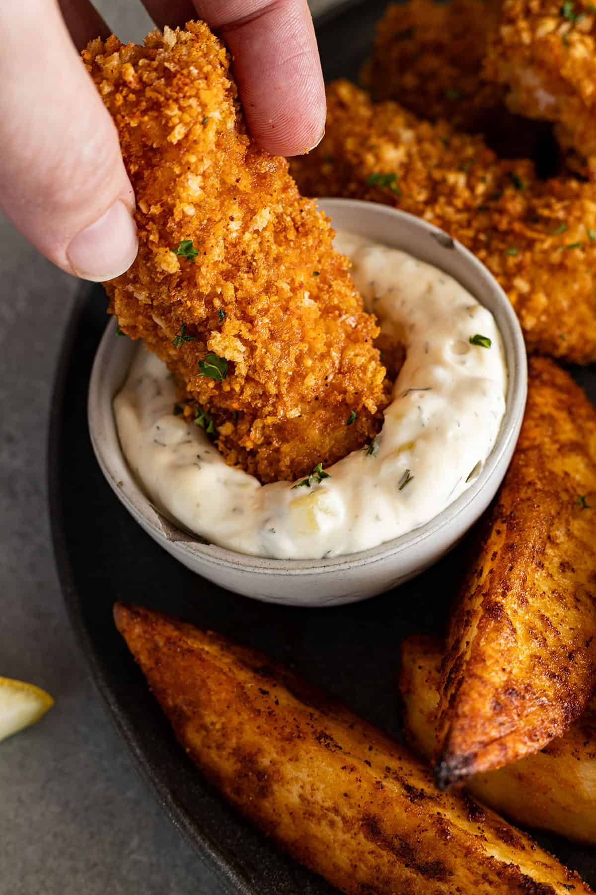 Fish stick dunking into homemade tartar sauce. 