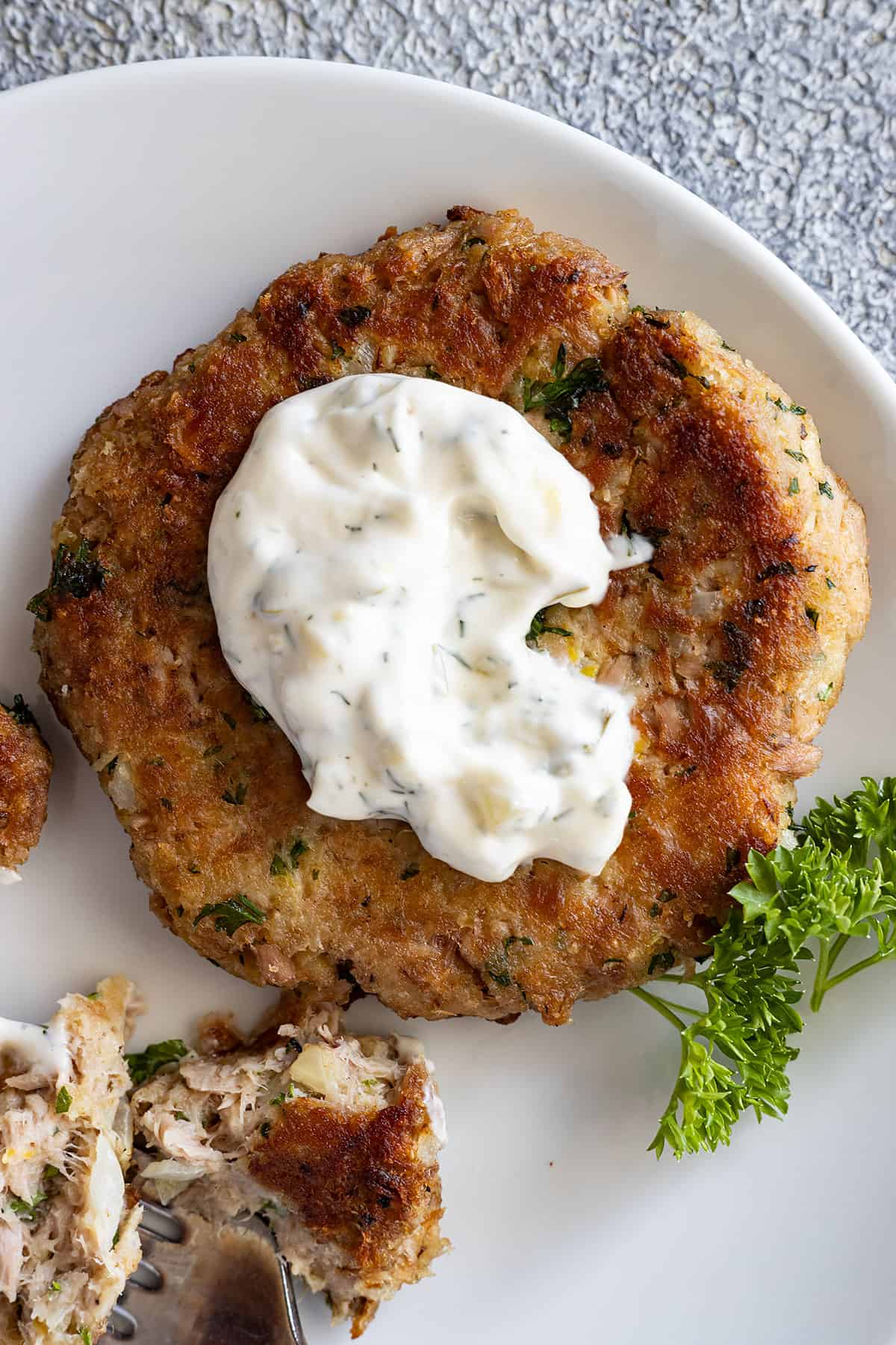 Overhead view of tuna cake with tartar sauce on top.