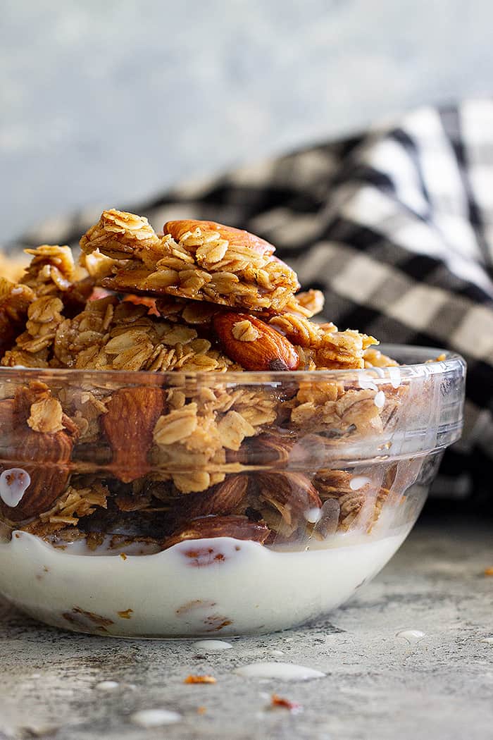 A bowl of honey almond granola with a splash of milk. 