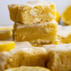 Stack of lemon brownies with sliced lemons around.