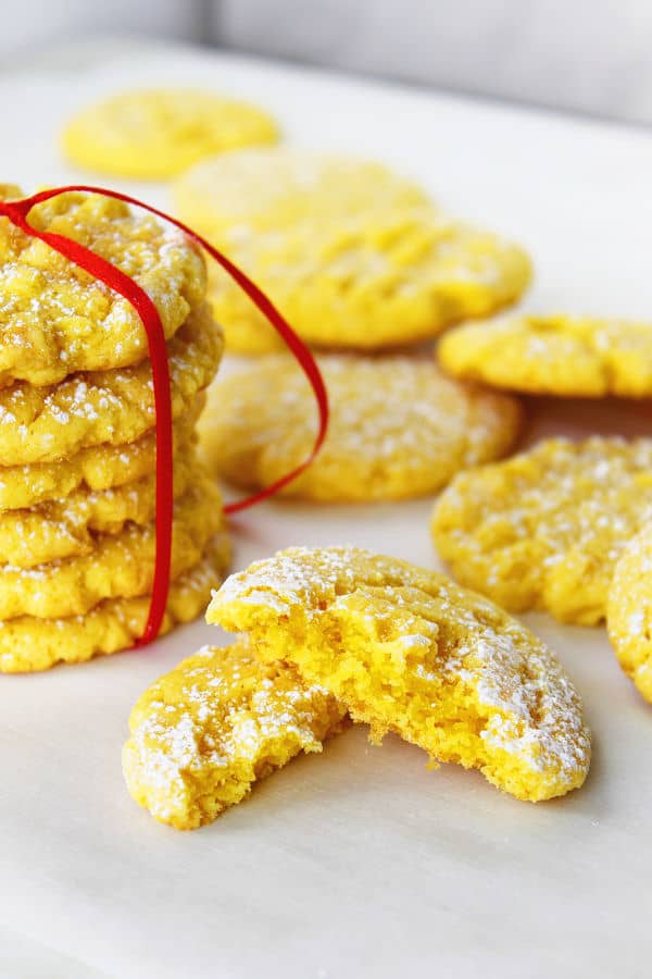 a pile of lemon cheesecake cookies tied in a bow with some in the background and one cut in half in the foreground