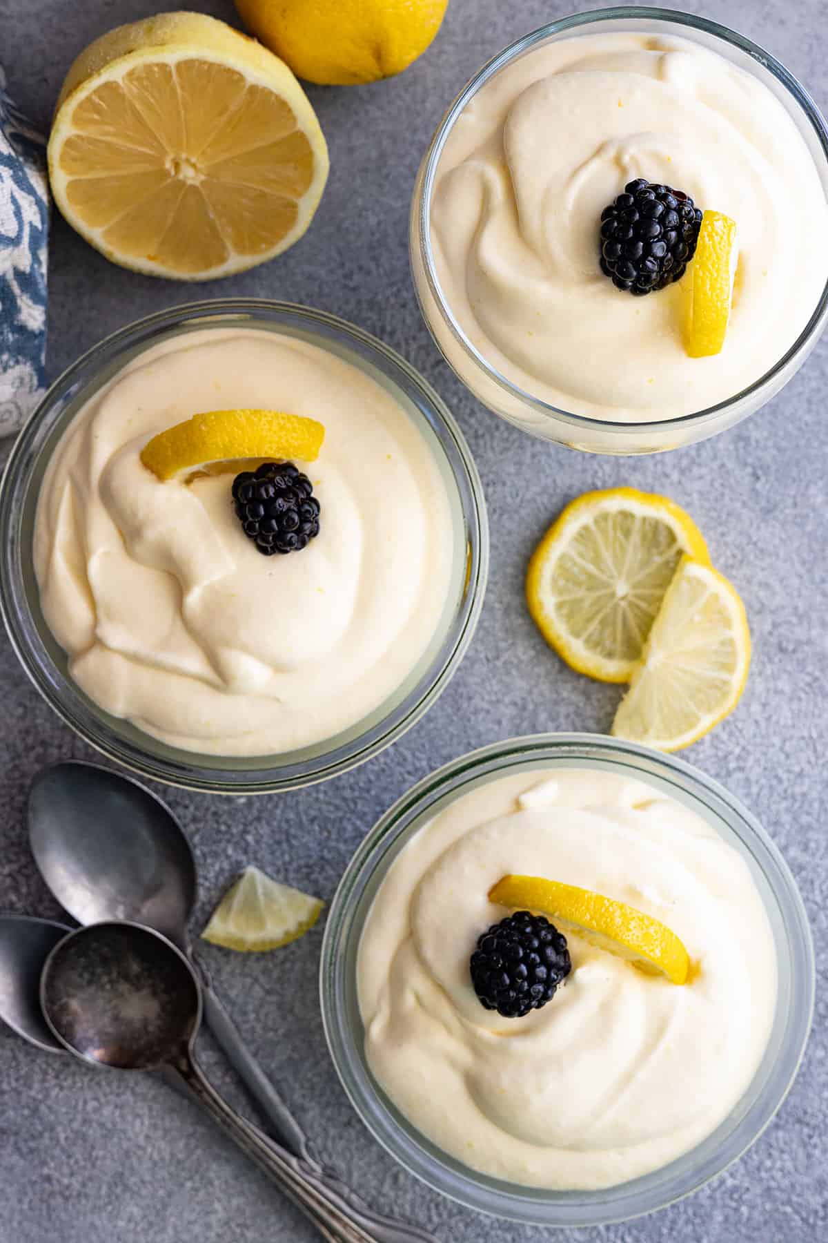 Overhead view of 3 bowls of mousse all garnished with a lemon slice and blackberry. 