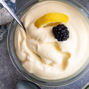 Overhead view of lemon mousse garnished a blackberry and lemon slice. Spoon in the mousse.