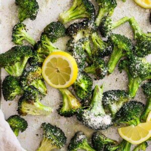 Top down view of lemon parmesan roasted broccoli on a sheet pan with lemon slices.