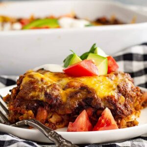 A slice of Mexican Casserole on a white plate with a fork.