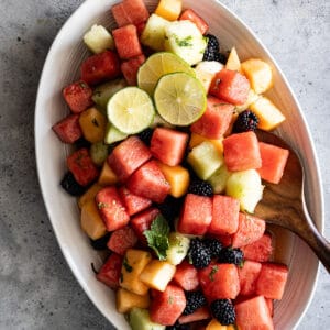 Overhead view of salad on a serving plate garnished with lime slices and mint.