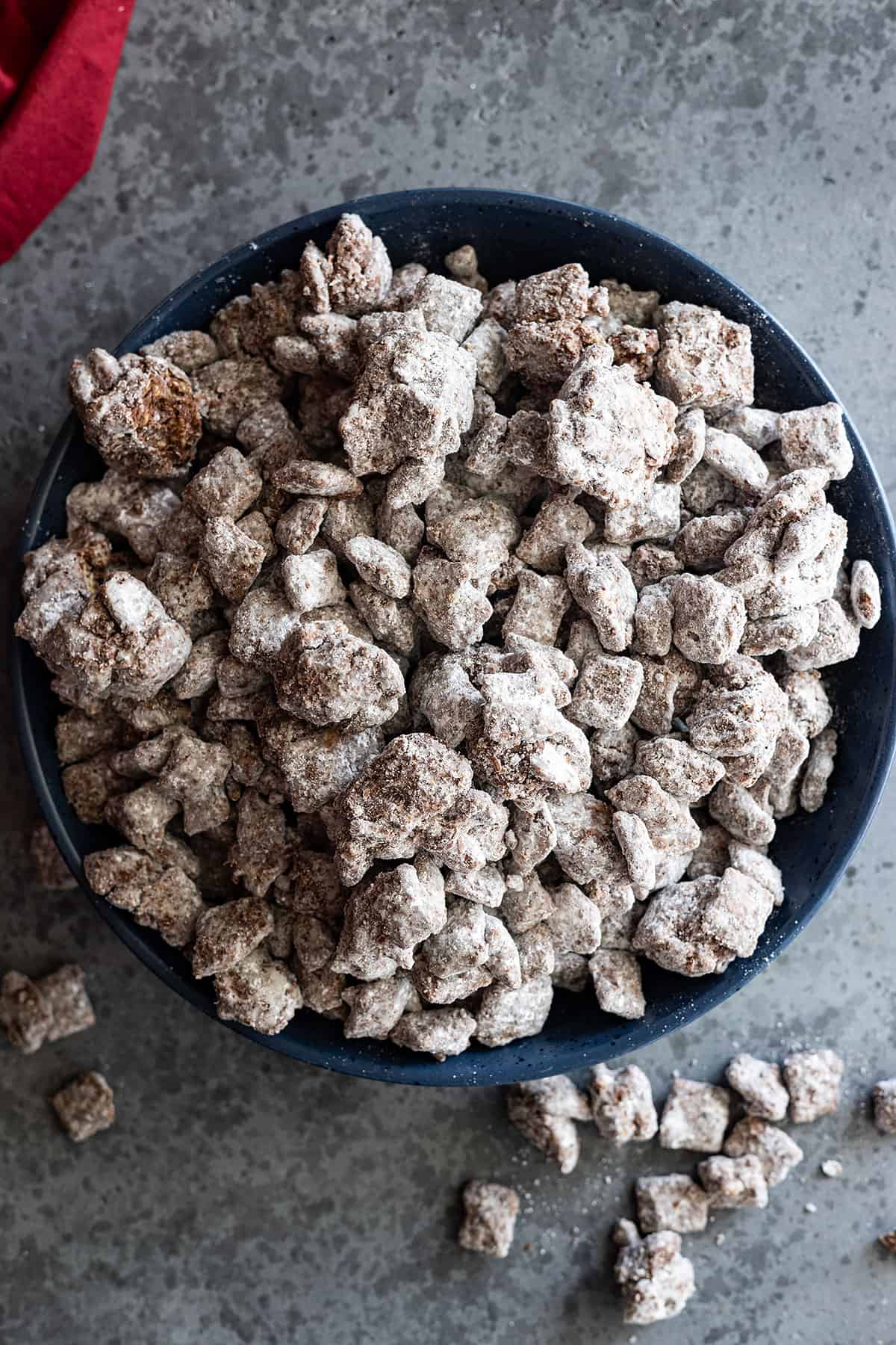 Overhead picture of muddy buddies in a large bowl. Some spilled out of the bowl. 