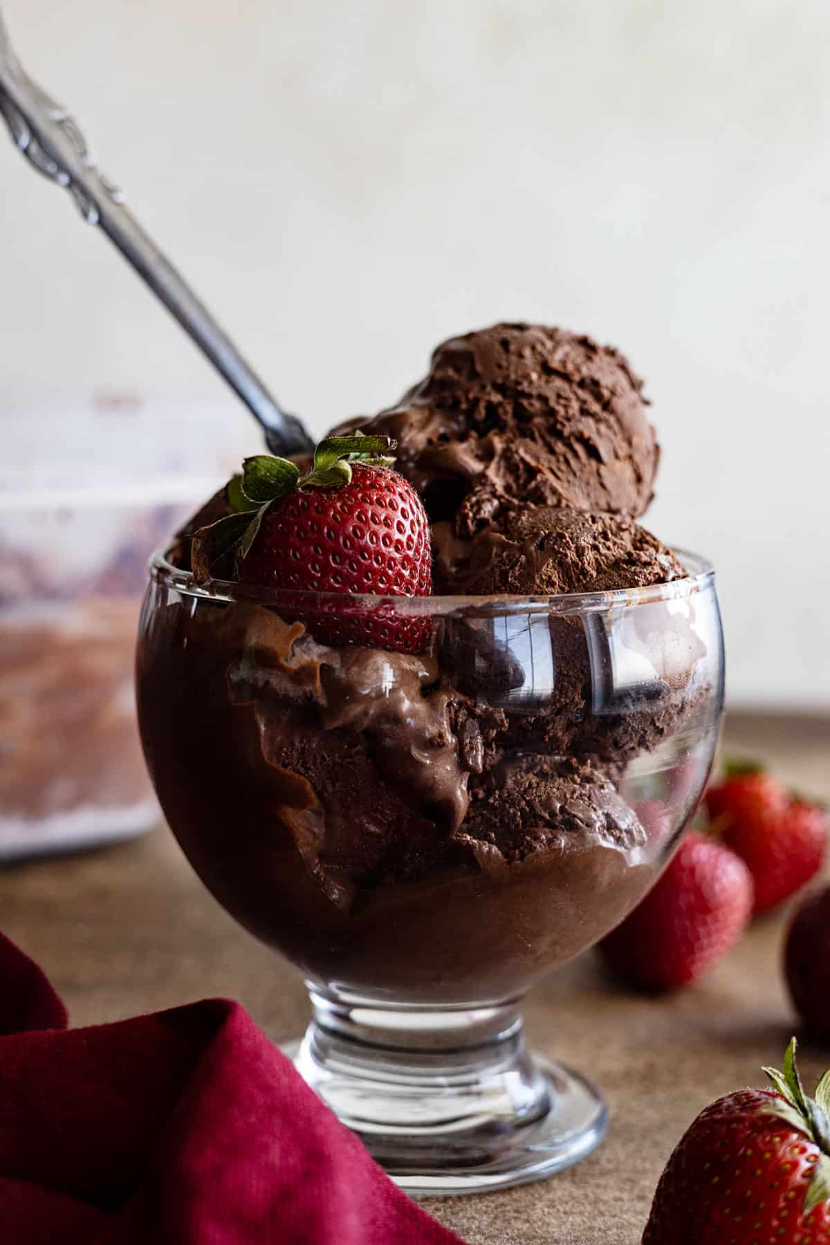 A cup of no-churn chocolate ice cream with a spoon and strawberry in it. 