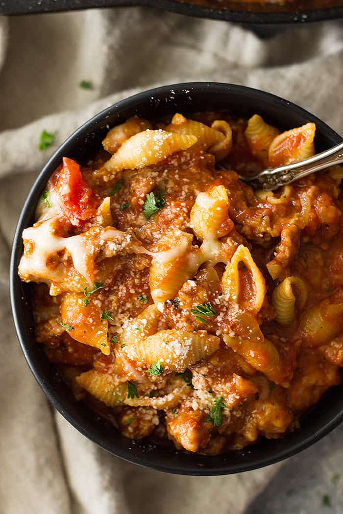 top shot of black bowl filled with noodles, parmesan, and red sauce