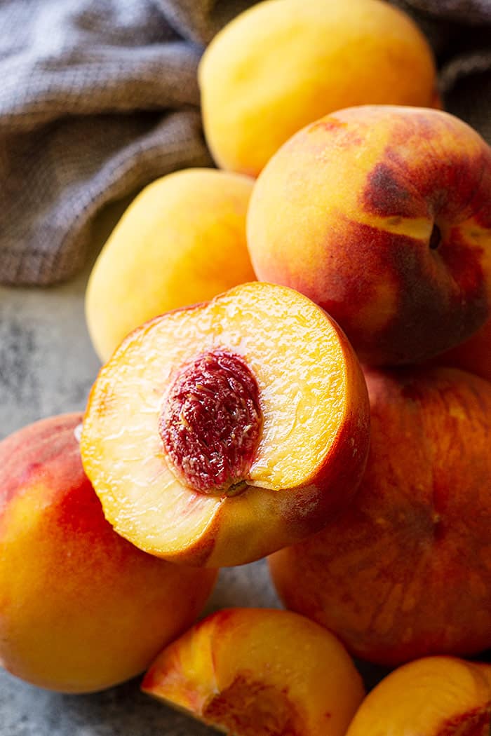 Fresh peaches. One is cut open.