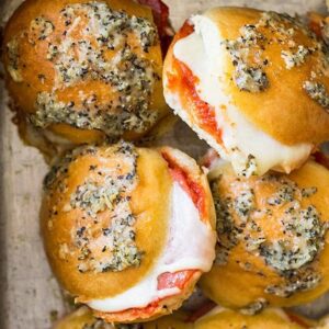Overhead view of sliders in a pan. Can see the melty cheese and yummy topping.