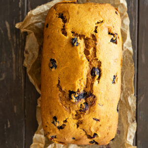 Overhead view of a loaf of pumpkin blueberry bread fresh from the oven.