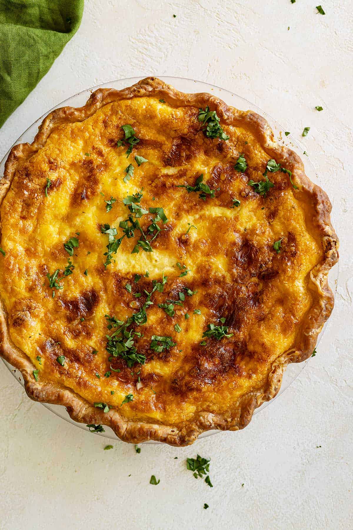 Overhead picture of quiche fresh from the oven and garnished with fresh chopped parsley. 