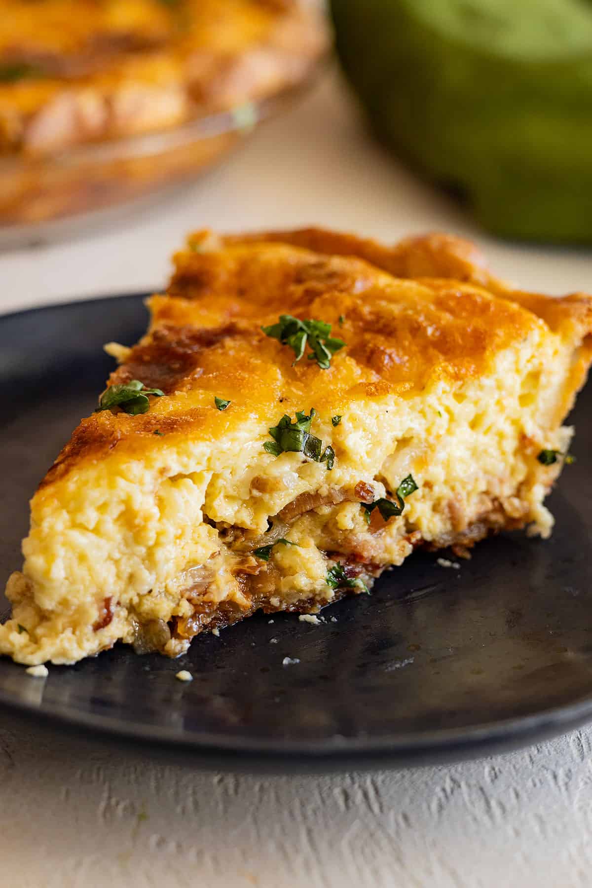 Slice of quiche on a black plate. 