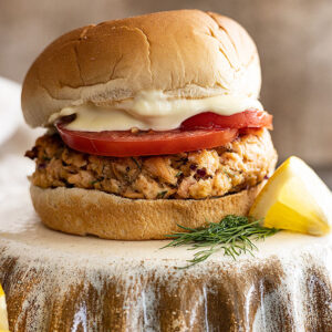 Straight on picture of burger topped with fresh tomato slices and mayo.