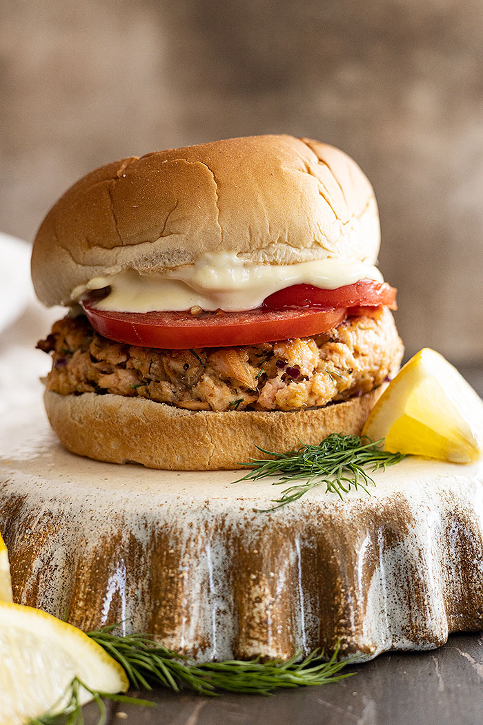Straight on picture of burger topped with fresh tomato slices and mayo.