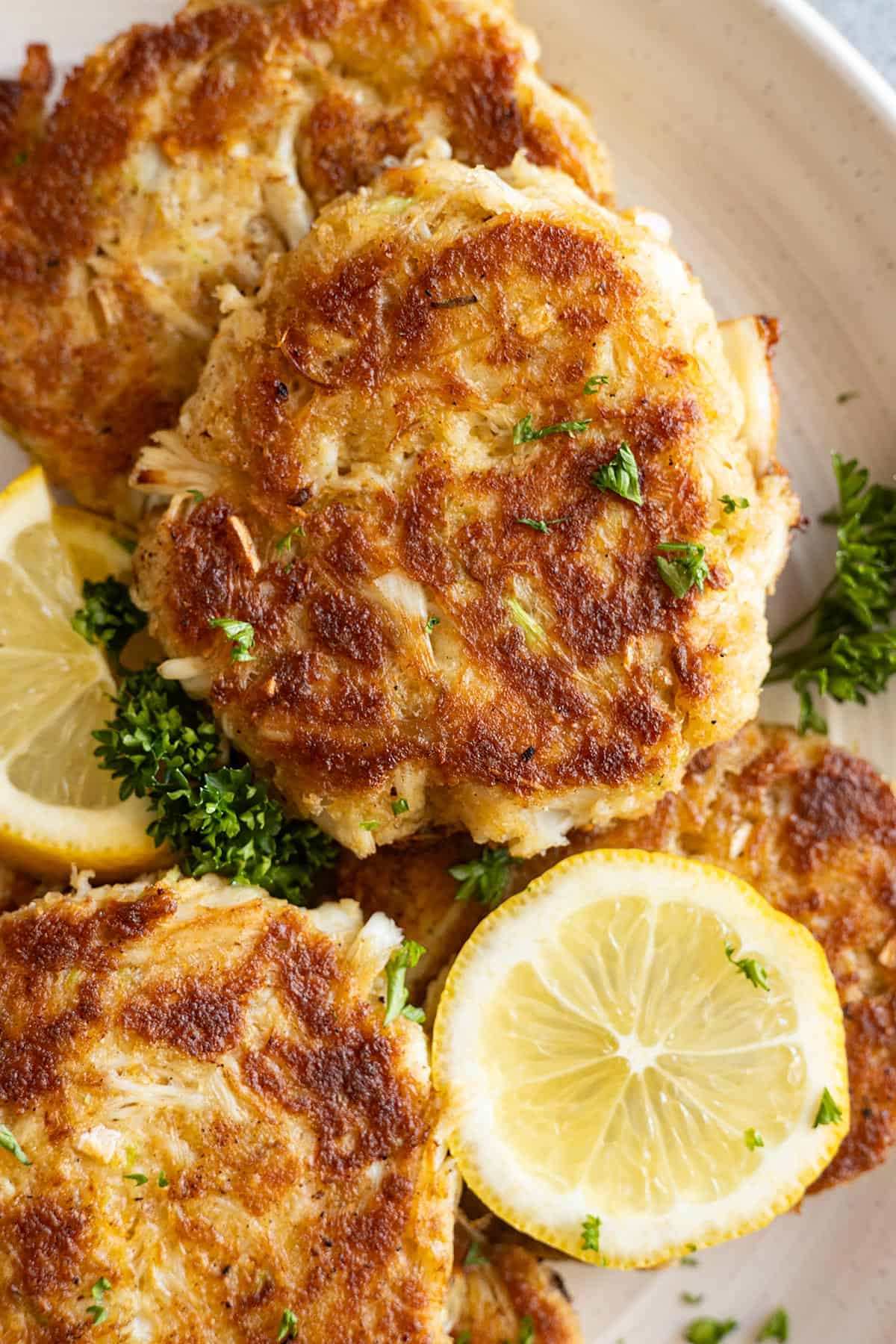 Close up of cakes on a plate garnished with fresh lemon and parsley. 