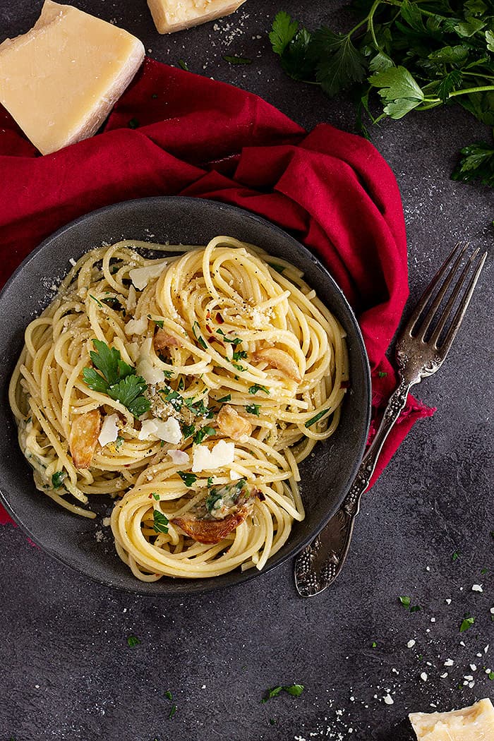 Pasta in a dish garnished with extra cheese and parsley.