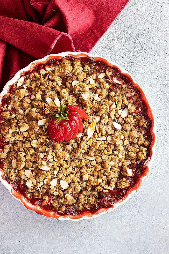 Overhead view of strawberry crisp fresh from the oven with a fresh strawberry fanned out on top for garnish.