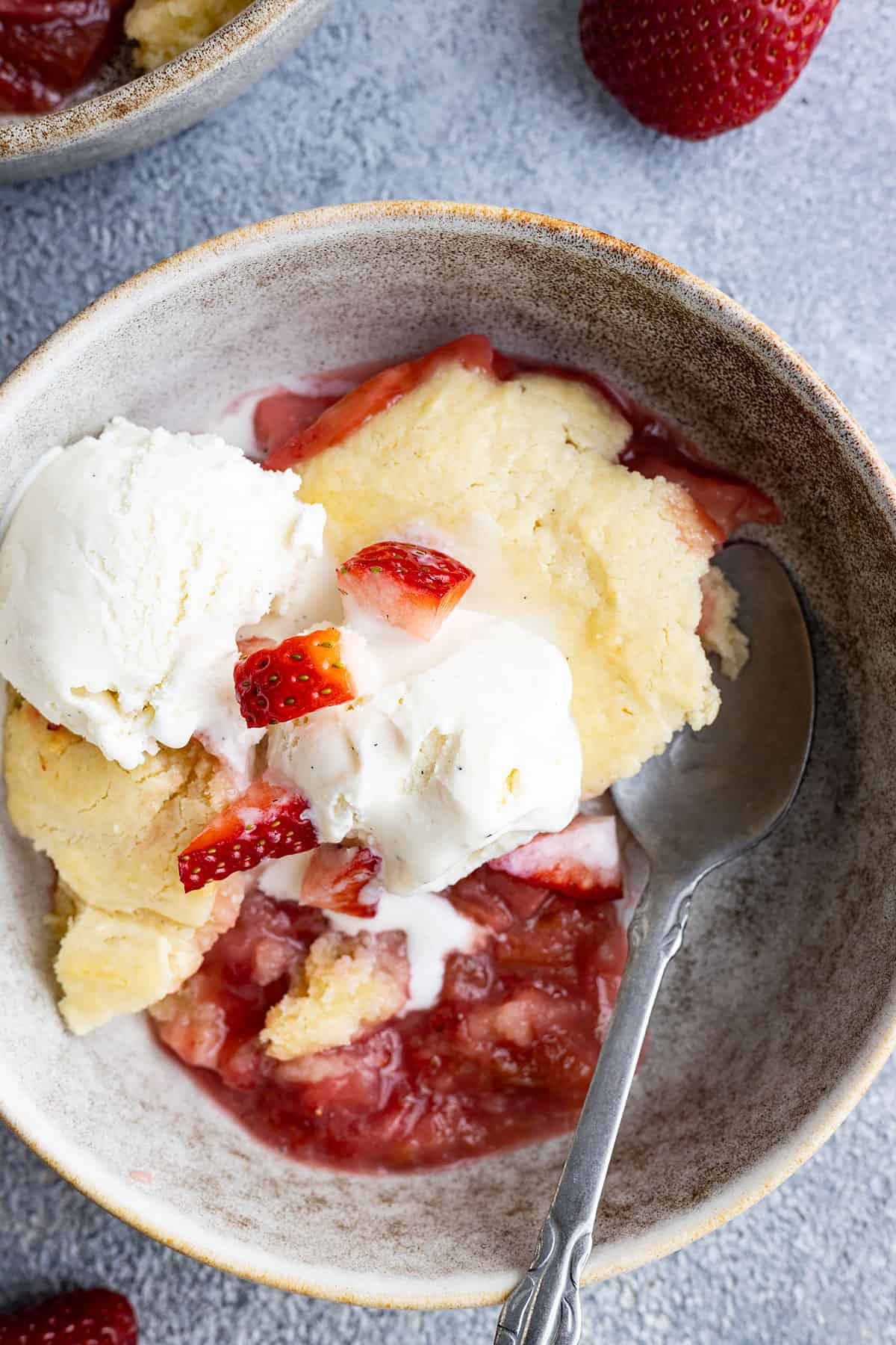 Overhead view of cake in a bowl with ice cream and a spoon. 
